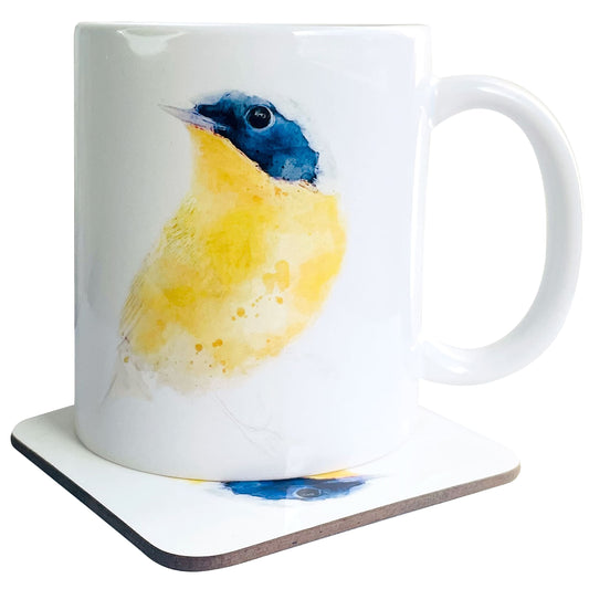 A glossy white ceramic mug with a watercolour abstract warbler art print in vivid yellow and blue tones, on top of a wooden coaster featuring a matching print, shown against a white backdrop.
