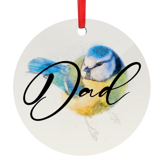 A circular white wooden glossy flat Christmas ornament featuring a watercolour yellow and blue blue tit bird art print and a personalised name in cursive text saying ‘Dad’ as an example, shown against a white backdrop